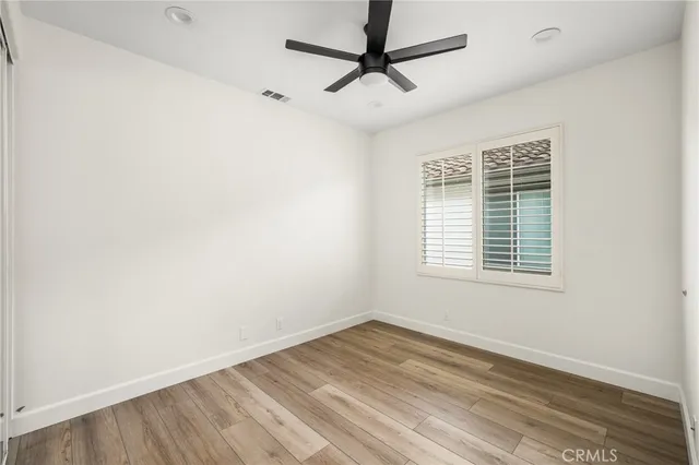a view of empty room with wooden floor and fan
