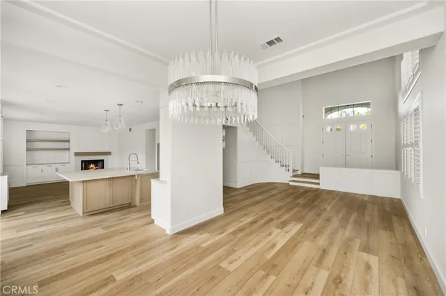 a view of a kitchen with kitchen island a sink wooden floor and stainless steel appliances