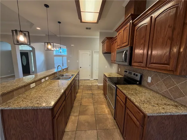 a kitchen with stainless steel appliances granite countertop a stove top oven a sink dishwasher and cabinets with wooden floor