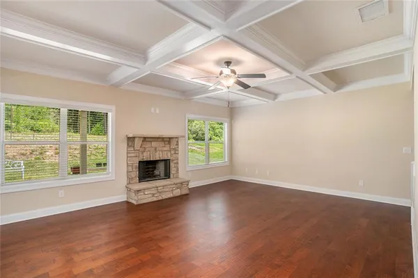 an empty room with windows fireplace and wooden floor