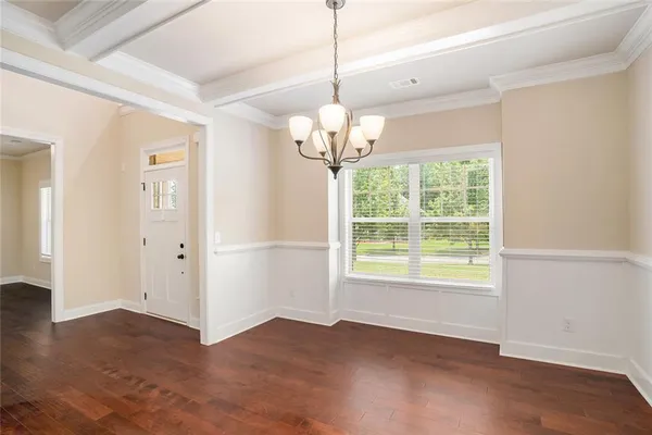 a view of a room with wooden floor chandelier and windows
