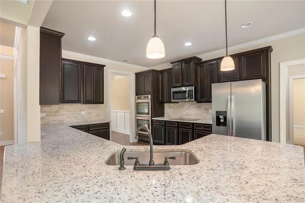 a kitchen with stainless steel appliances kitchen island granite countertop a refrigerator and a sink