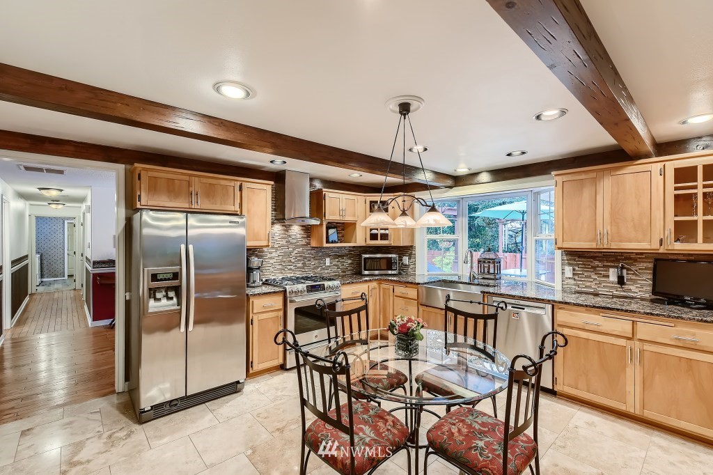 32219 22nd Avenue Southwest Federal Way, WA 98023 - Photo 11 of 36 a kitchen with granite countertop a table chairs microwave and refrigerator