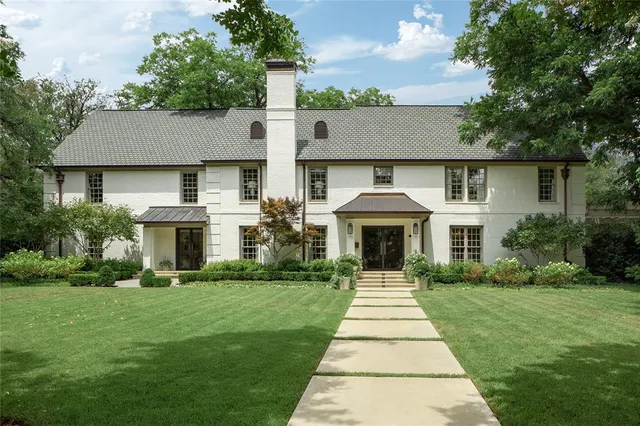 a front view of a house with a garden and trees