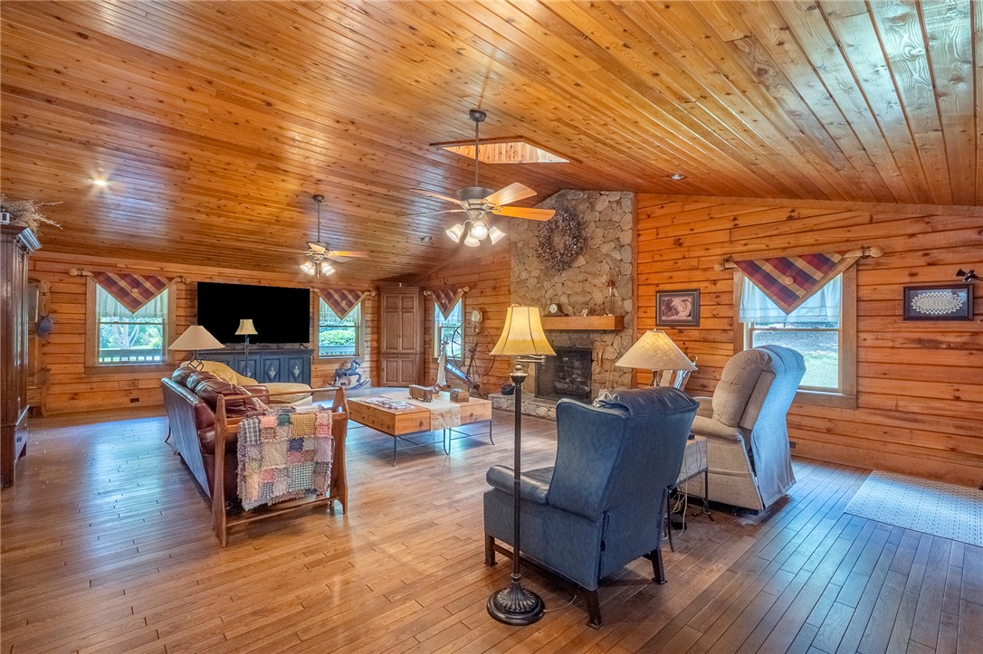 911 State Rd S-4-203 Belton, SC 29627 - Photo 18 of 49 A rustic cabin living area features extensive wood paneling and a commanding stone fireplace.