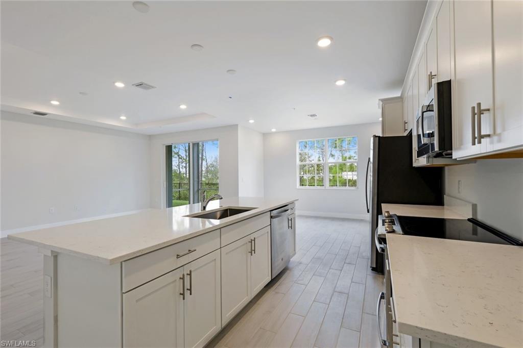 a kitchen with a sink stainless steel appliances cabinets and a window