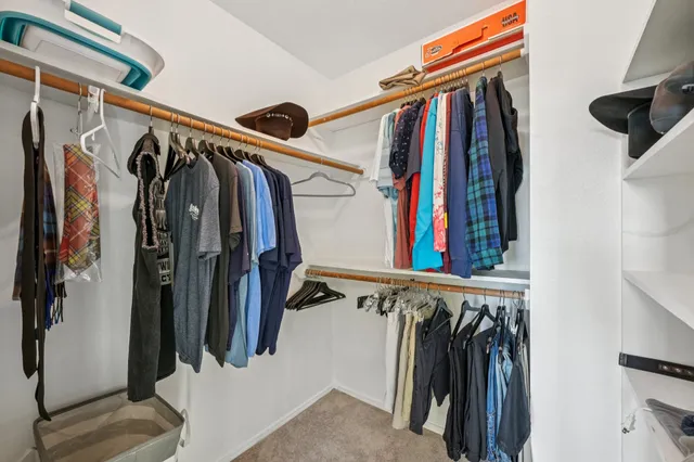 a view of walk in closet with clothes and shoes