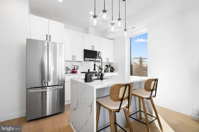 a kitchen with stainless steel appliances granite countertop a refrigerator a stove a sink dishwasher a dining table and chairs with wooden floor