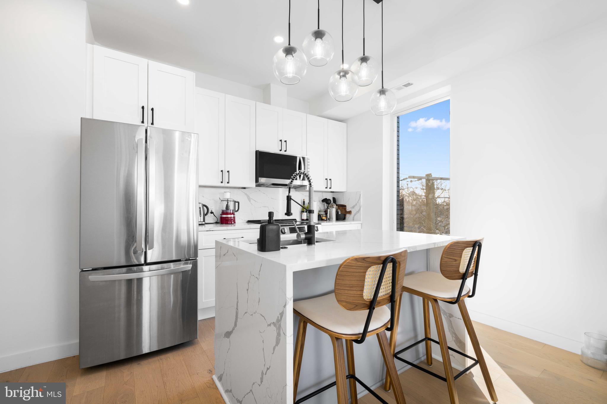 30 Kennedy Street Northwest, Unit 14 Washington, DC 20011 - Photo 11 of 40 a kitchen with stainless steel appliances granite countertop a refrigerator a stove a sink dishwasher a dining table and chairs with wooden floor