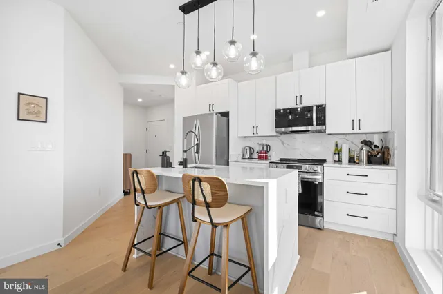 a kitchen with stainless steel appliances kitchen island granite countertop a table chairs microwave and cabinets