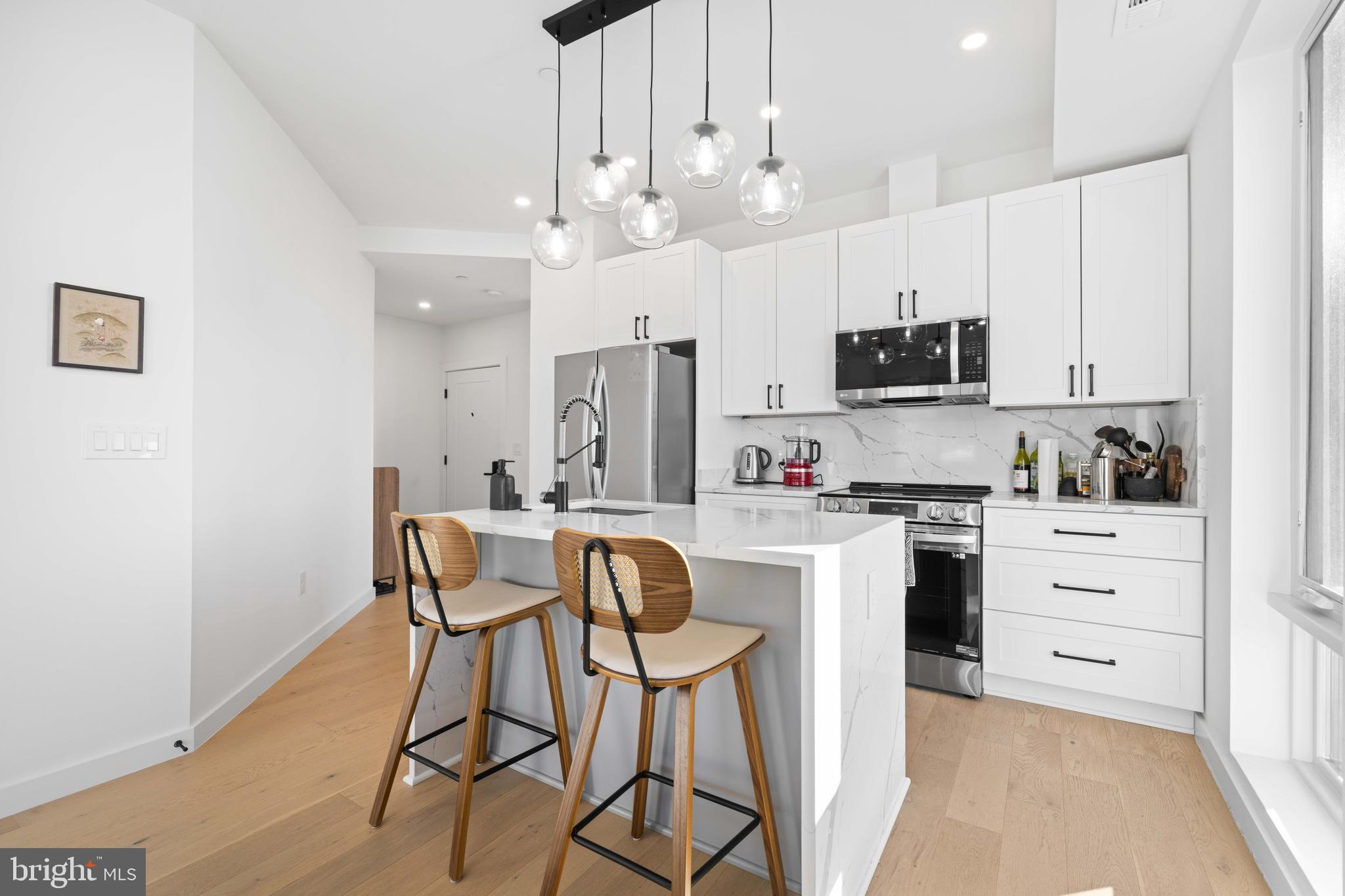 30 Kennedy Street Northwest, Unit 14 Washington, DC 20011 - Photo 3 of 40 a kitchen with stainless steel appliances kitchen island granite countertop a table chairs microwave and cabinets