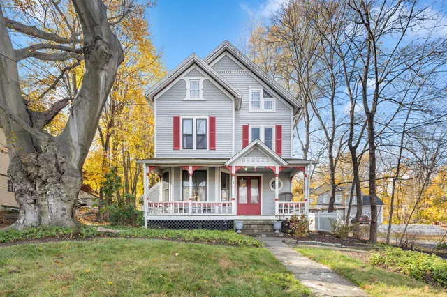 a view of a white house with a big yard and large trees