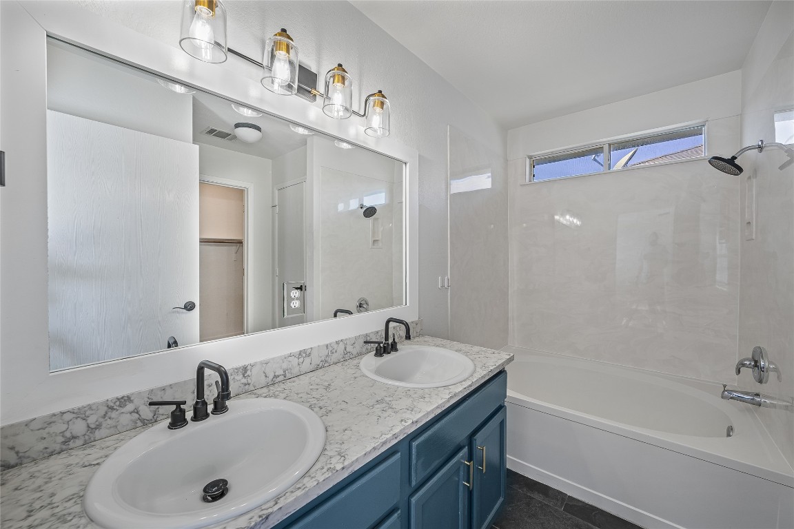 12517 Campana Drive Del Valle, TX 78617 - Photo 11 of 15 a bathroom with a granite countertop sink a mirror a bathtub and shower