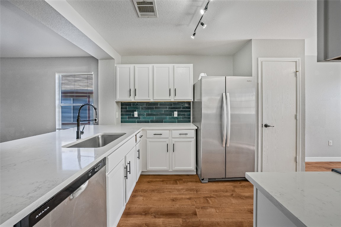 12517 Campana Drive Del Valle, TX 78617 - Photo 4 of 15 a kitchen with stainless steel appliances granite countertop a refrigerator a sink and white cabinets