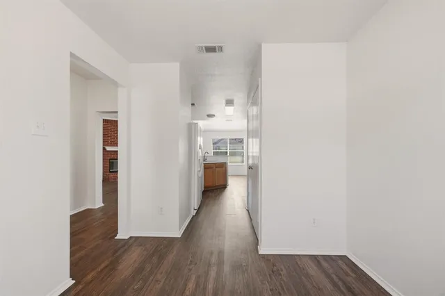 a view of a hallway with wooden floor and a bathroom