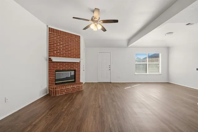 an empty room with wooden floor fireplace and windows