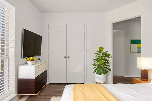 a bedroom with a bed table and a flat screen tv