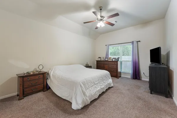 a spacious bedroom with a bed and a flat screen tv