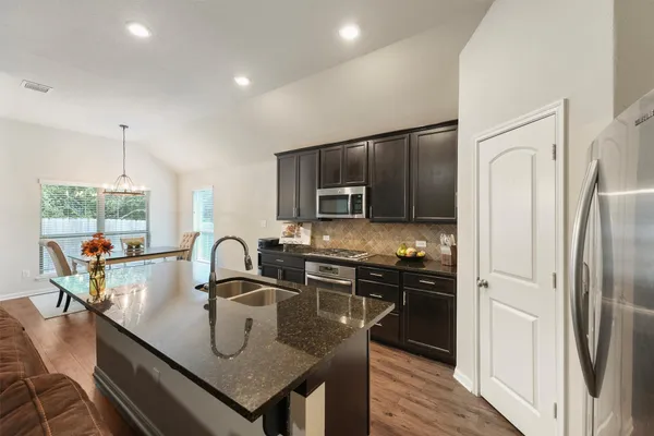 a kitchen with stainless steel appliances granite countertop a sink a stove and refrigerator