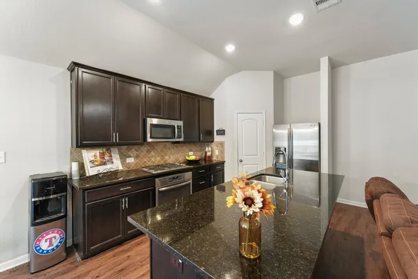 a kitchen with stainless steel appliances granite countertop a sink refrigerator and microwave
