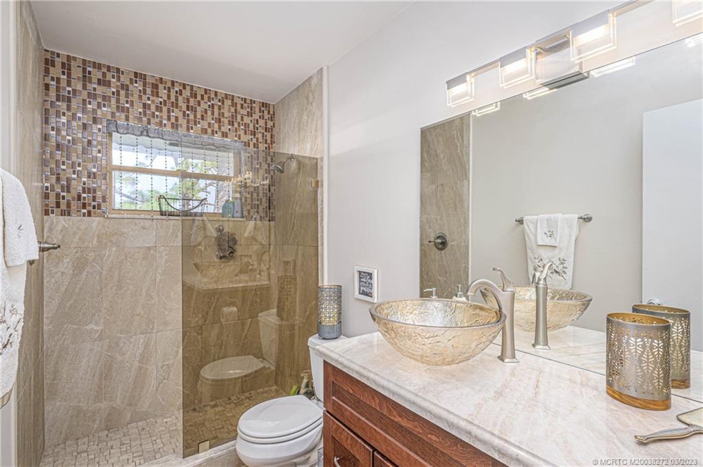 2929 Southeast Ocean Boulevard, Unit 1436 Stuart, FL 34996 - Photo 10 of 18 a bathroom with a granite countertop sink toilet a shower and a mirror