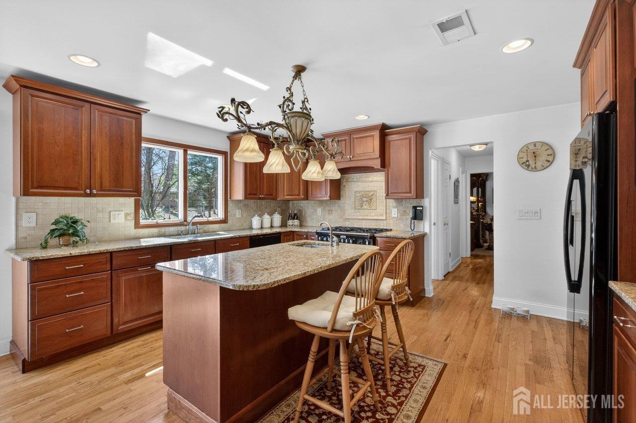 15 Cherokee Road East Brunswick, NJ 08816 - Photo 14 of 45 a kitchen with stainless steel appliances granite countertop wooden cabinets a refrigerator a sink a stove a dining table and chairs with wooden floor