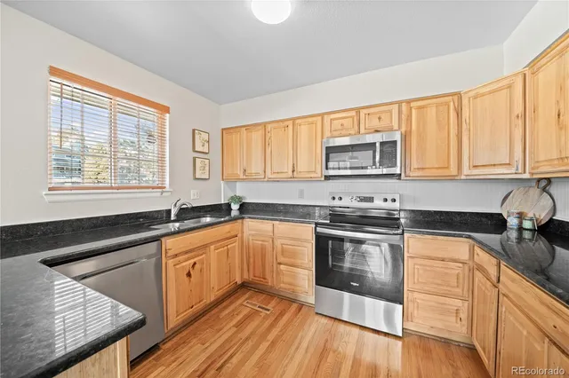 a kitchen with granite countertop wooden cabinets stainless steel appliances a window and a sink