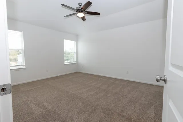 an empty room with windows and fan