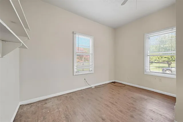 an empty room with wooden floor and windows