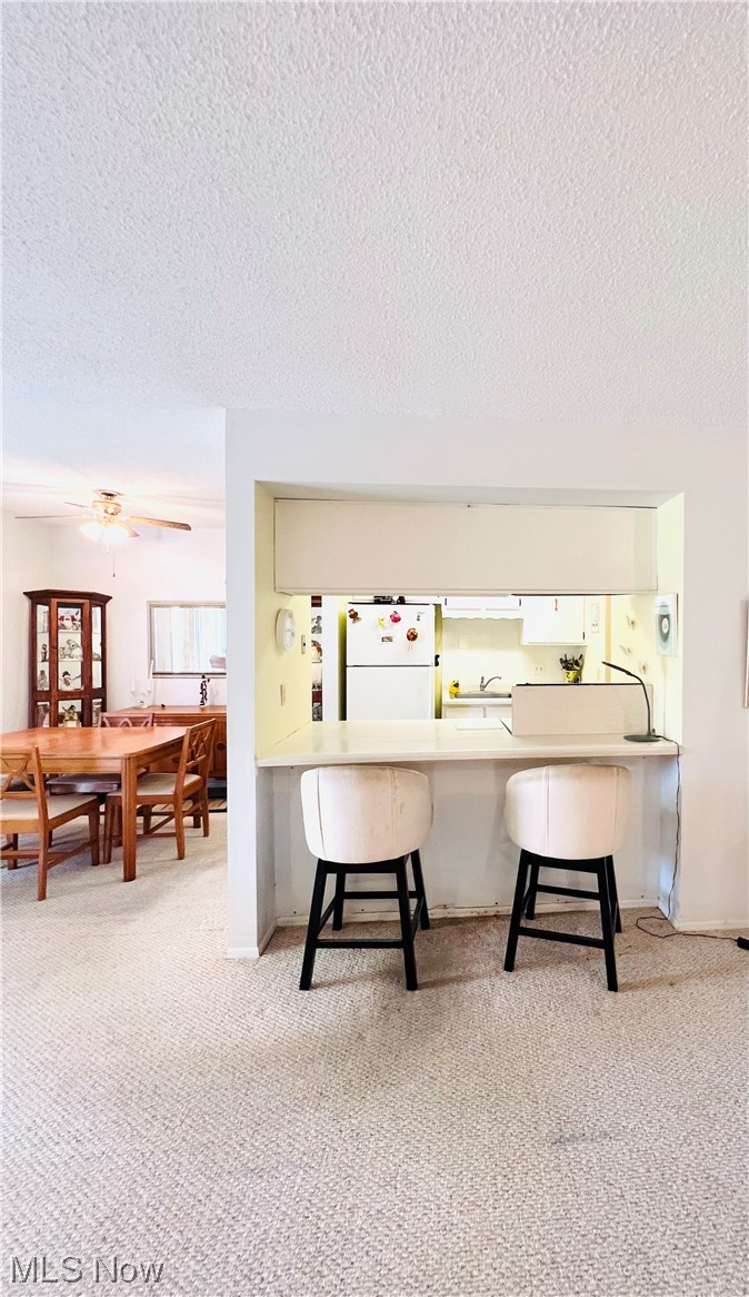 4940 Friar Road, Unit B Stow, OH 44224 - Photo 9 of 33 Kitchen with white refrigerator, light colored carpet, a kitchen bar, and a textured ceiling