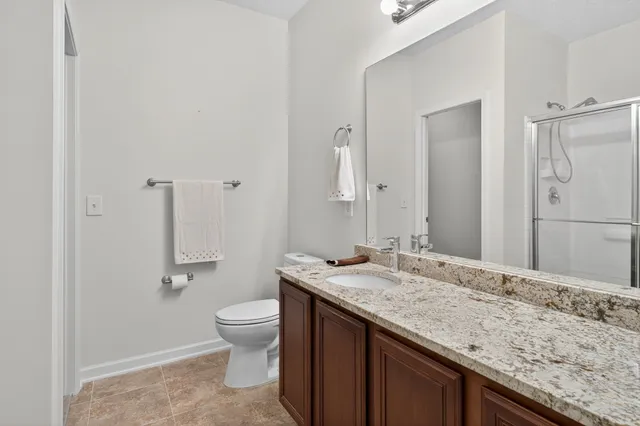 a bathroom with a granite countertop sink a toilet and a large mirror