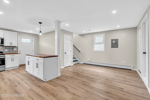 a kitchen with white cabinets and wooden floor