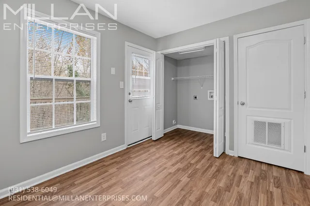 a view of an empty room with wooden floor and a window