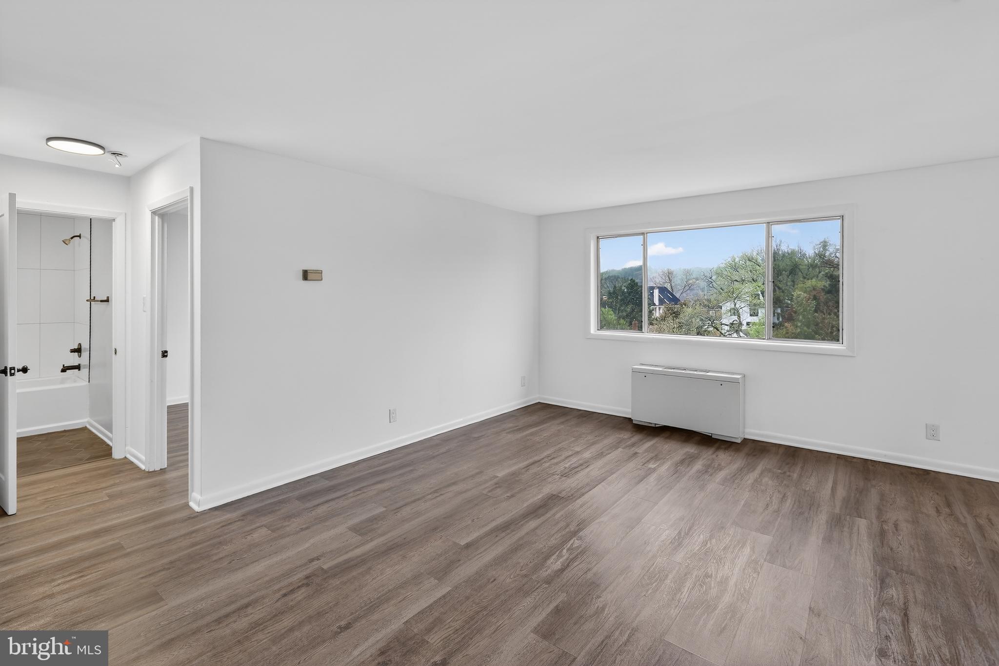 4570 MacArthur Boulevard Northwest, Unit 208 Washington, DC 20007 - Photo 8 of 17 an empty room with wooden floor and windows