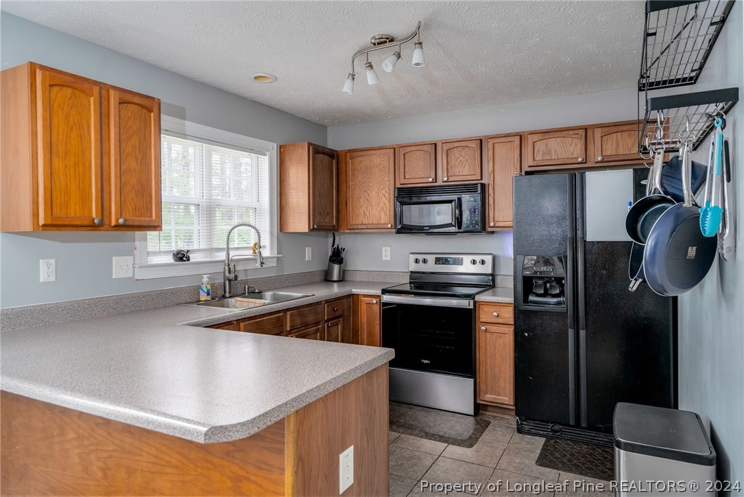 3590 Calloway Road Raeford, NC 28376 - Photo 8 of 44 a kitchen with stainless steel appliances granite countertop a sink a stove a refrigerator cabinets and a window