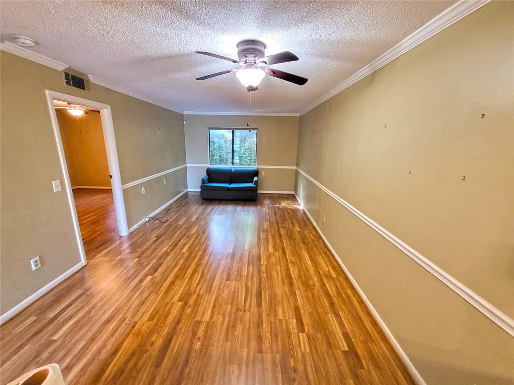 150 Ligon Street, Unit 1001 Clemson, SC 29631 - Photo 10 of 29 A long living room features crown molding, a ceiling fan, and rich hardwood flooring.