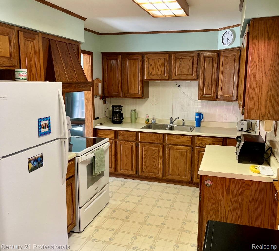 2903 Lake Angelus Road Waterford, MI 48329 - Photo 6 of 17 Kitchen featuring wood cabinetry, laminate countertops, a double basin stainless steel sink, and patterned vinyl flooring