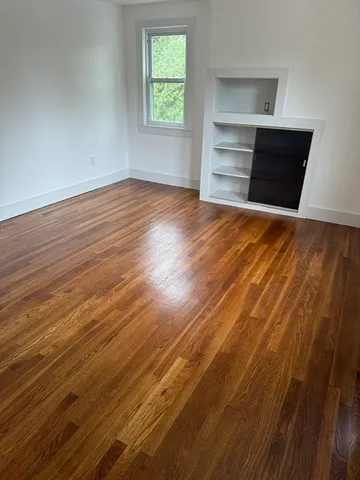 an empty room with wooden floor closet and windows