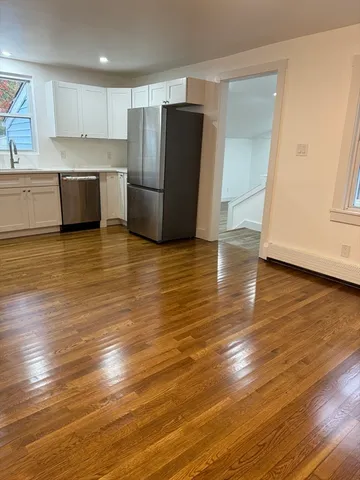 a view of a kitchen with wooden floor and stainless steel appliances