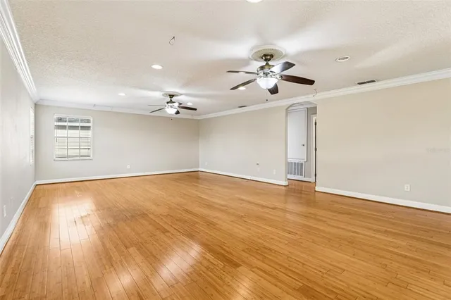 an empty room with chandelier fan and windows