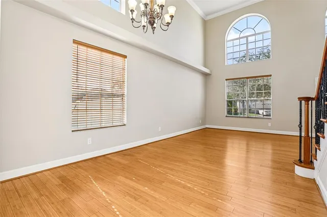 a view of an empty room with wooden floor and a kitchen