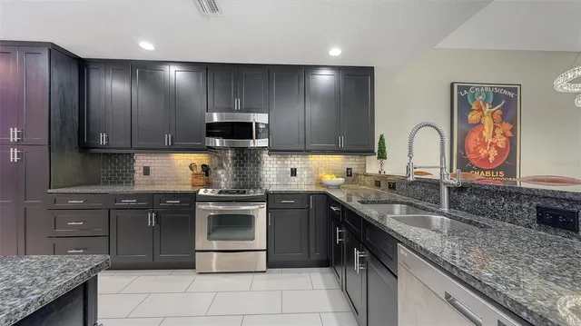 a kitchen with stainless steel appliances granite countertop a sink stove and cabinets