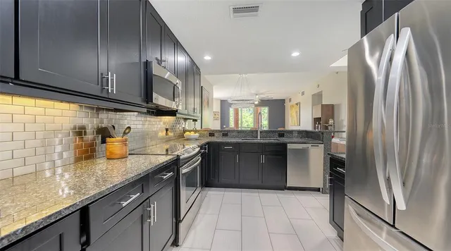 a kitchen with stainless steel appliances granite countertop a refrigerator a sink and wooden cabinets