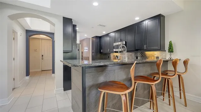 a kitchen with stainless steel appliances granite countertop a table chairs in it and wooden floors