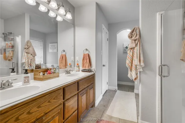 a bathroom with a double vanity sink mirror and shower