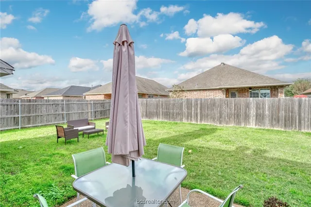 a backyard of a house with table and chairs a fire pit and outdoor seating
