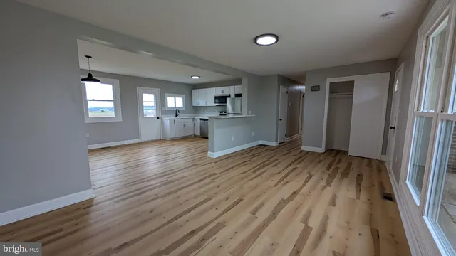 an empty room with wooden floor and a kitchen