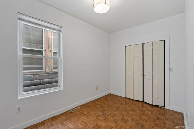 a view of an empty room with window and closet area