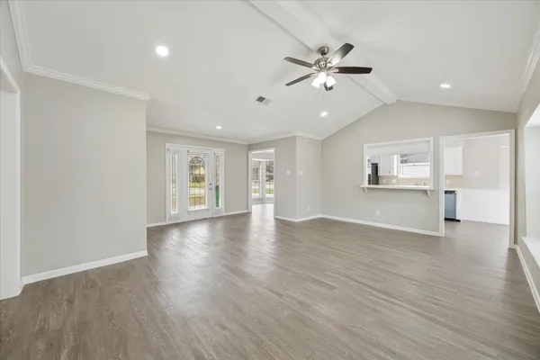 a view of an empty room with wooden floor and a ceiling fan