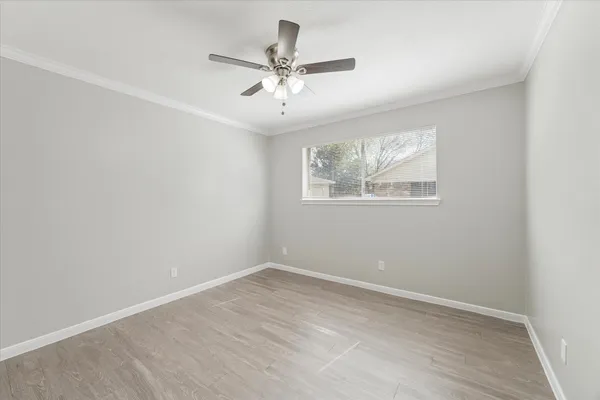 an empty room with wooden floor fan and windows
